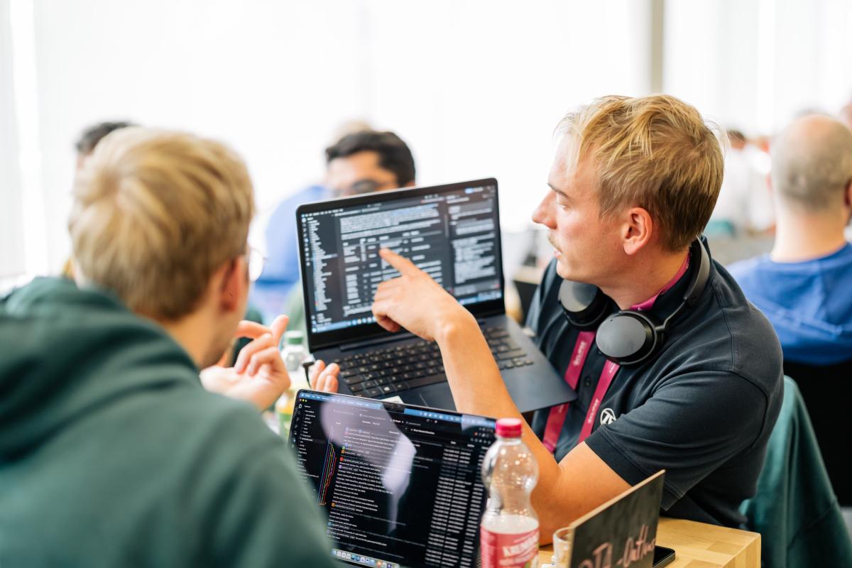 Two men looking at source code on a laptop screen