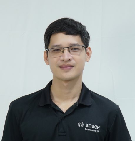 Young man with glasses and black Bosch shirt smiling at the camera