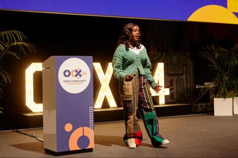 Woman in green jacket presenting on a conference stage