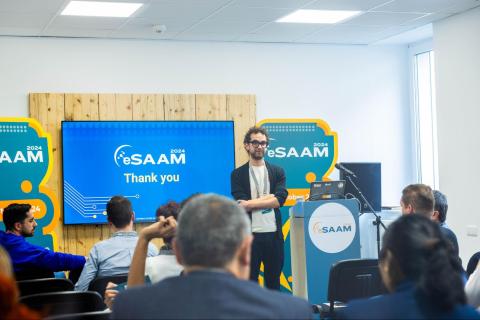 Conference room with a man with glasses presenting and audience