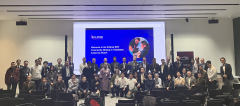 Large group photo of attendees at the Eclipse SDV Community Meetup in Yokohama, standing and kneeling in a conference room. Behind them, a presentation screen reads ‘Welcome to the Eclipse SDV Community Meetup in Yokohama hosted by Bosch,’ with the Eclipse Foundation logo displayed