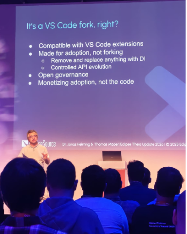 Conference speaker presenting a slide titled ‘It’s a VS Code fork, right?’ explaining compatibility with VS Code extensions, focus on adoption over forking, controlled API evolution, open governance, and monetisation strategy.